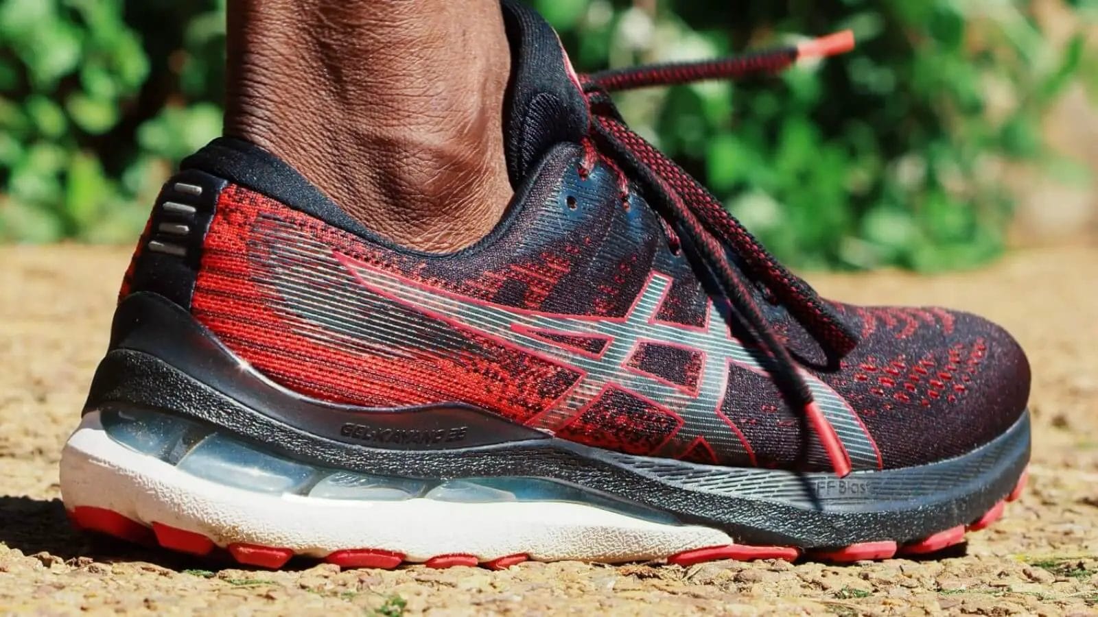 Details of the rear of the asics gel kayano 28 shoe while someone is running on pavement.