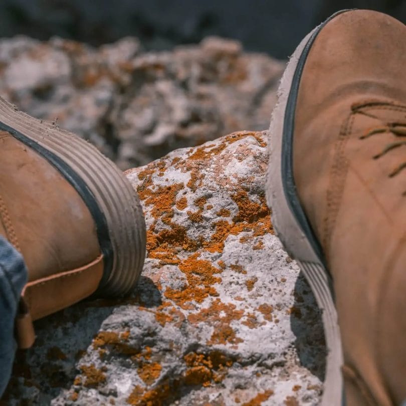Close up details of design features of a pair of boots on a rock during hiking excursion.