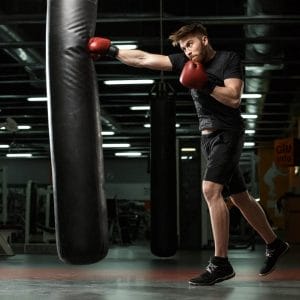 Man in black with black boxing shoes training on heavy bag