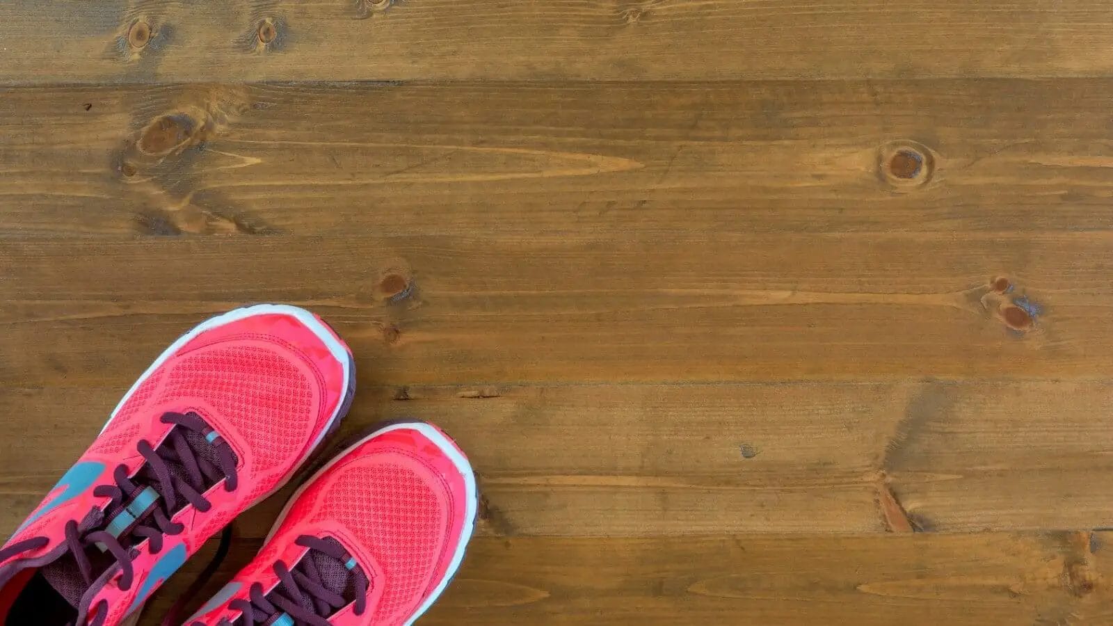 Pink running shoes for plantar fasciitis on wooden floor.