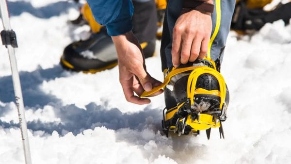 Person strapping on ice traction crampons for mountaineering