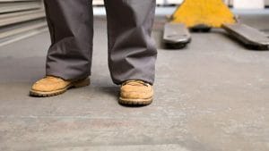 Tan safety boots in front of a skid at a warehouse with concrete floors