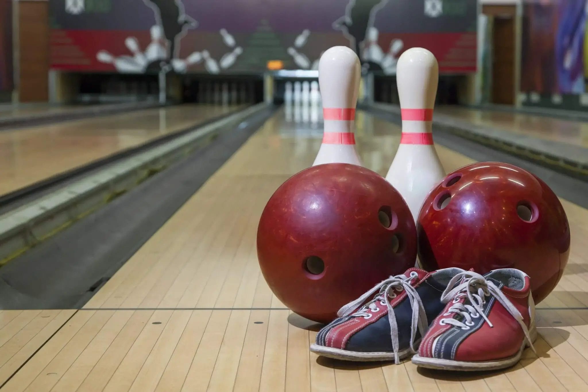 Detail of two bowling pins, two bowling balls, and one pair of bowling shoes on a lane