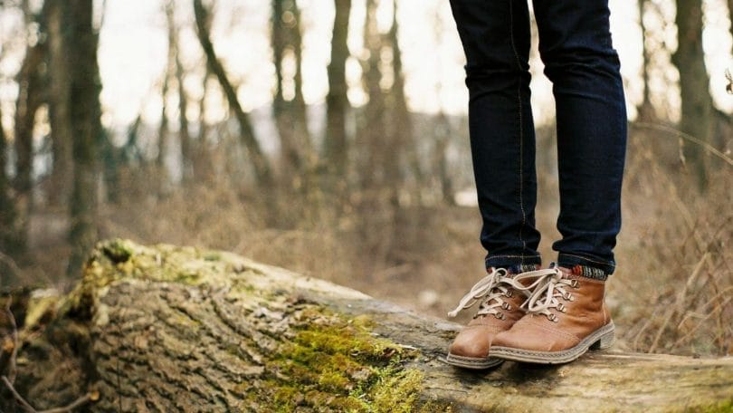 Woman with brown leather hiking boots and goodyear welt construction standing on a log.